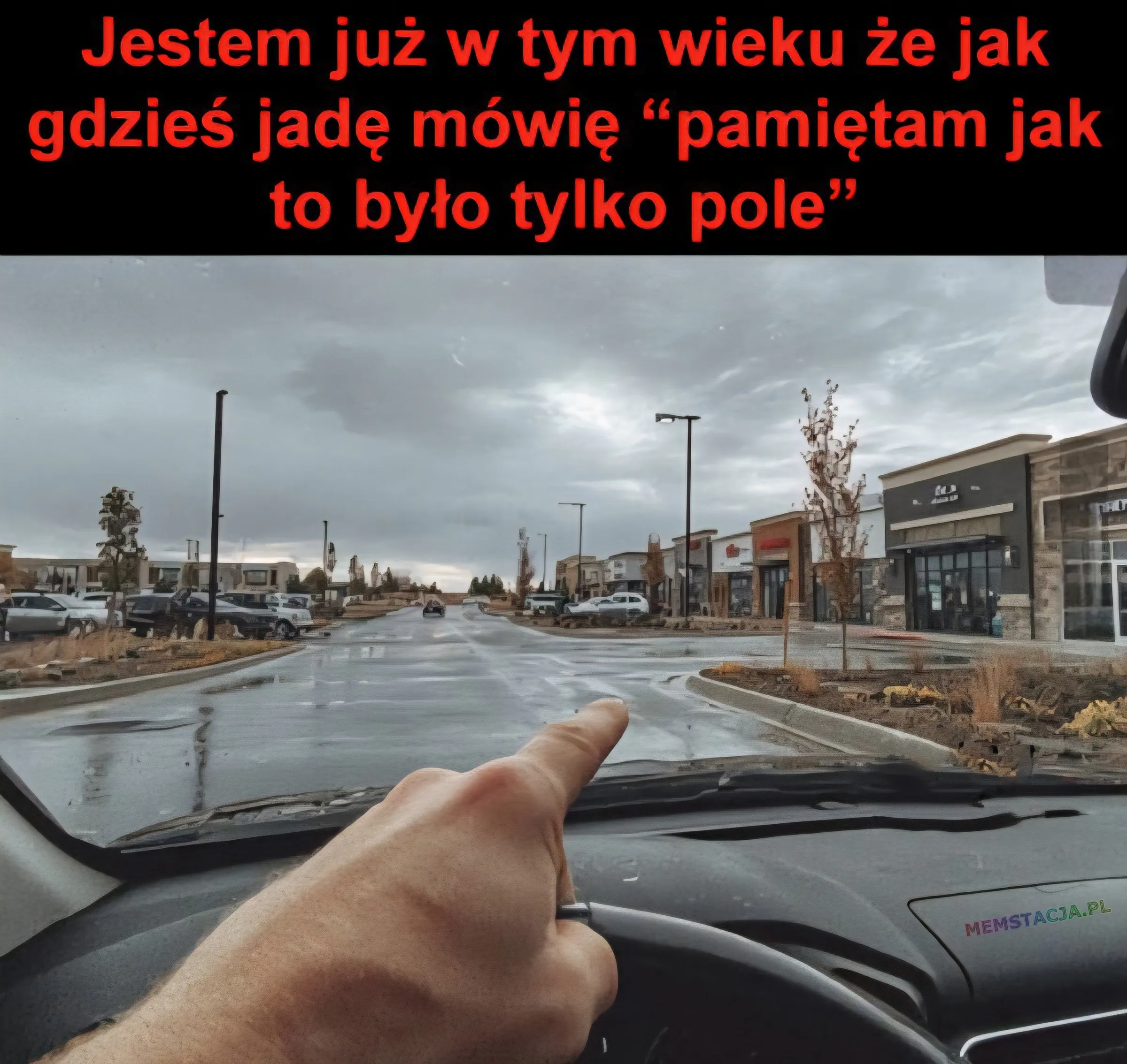 Mem o tytule: Kiedy艣 to by艂o... pole 馃槄 Jestem ju偶 w tym wieku 偶e jak gdzie艣 jad臋 m贸wi臋 "pami臋tam jak to by艂o tylko pole": R臋ka trzymaj膮ca kierownic臋 samochodu jad膮cego ulic膮 z drzewami i budynkami po obu stronach.
