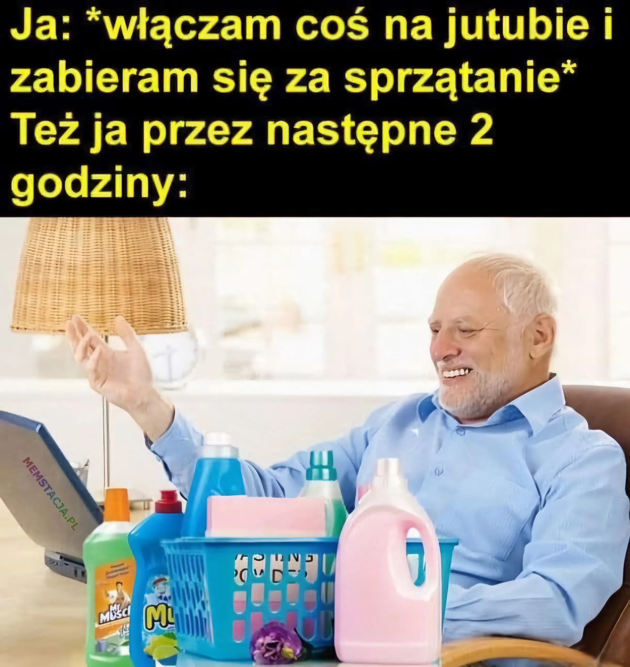 Ja: włączam coś na jutubie i zabieram się za sprzątanie. Też ja przez następne dwie godziny: Zdjęcie mężczyzny siedzącego z uśmiechem na twarzy przy laptopie i środkami czyszczącymi na stole.